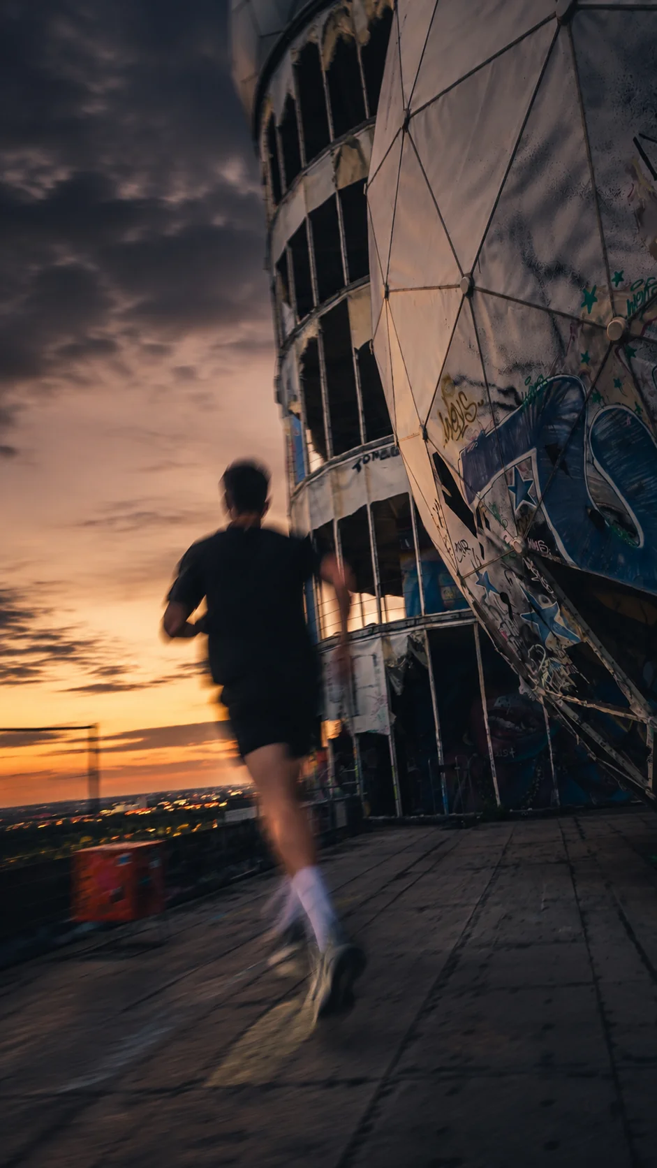 Leicht verschwommener Läufer joggt vor der Kuppel des Teufelsbergs bei Sonnenuntergang.